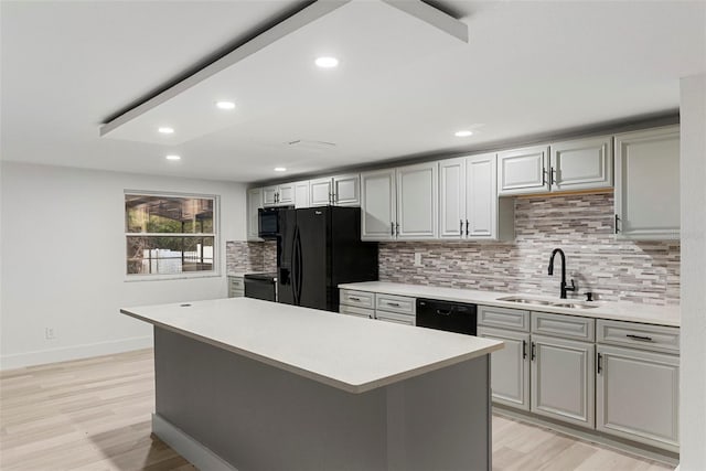 kitchen with sink, gray cabinets, black appliances, and a center island