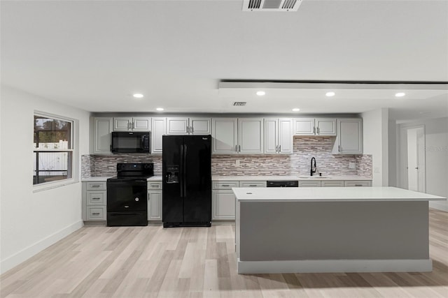 kitchen featuring tasteful backsplash, gray cabinets, sink, and black appliances