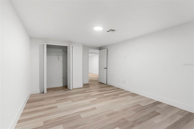 unfurnished bedroom with light wood-type flooring and a closet