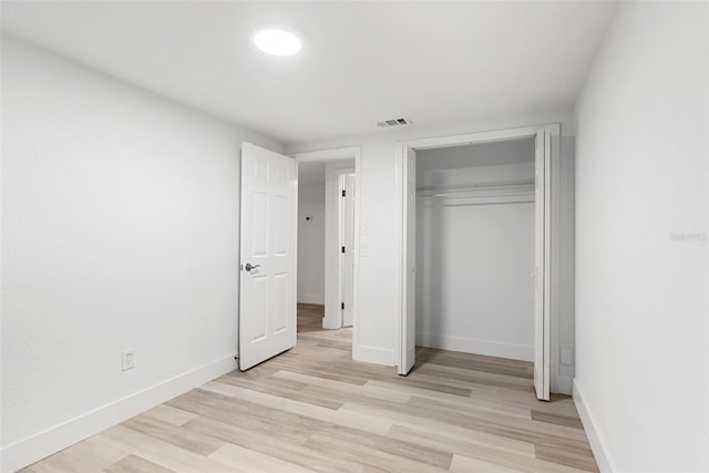 unfurnished bedroom featuring light hardwood / wood-style flooring and a closet