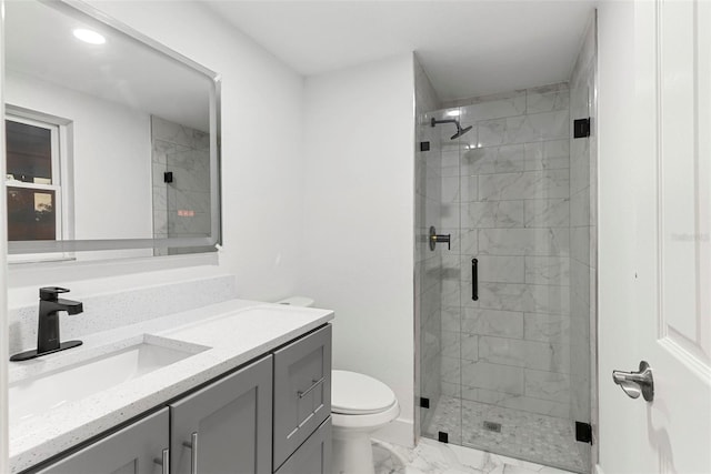 bathroom with vanity, a shower with door, and toilet