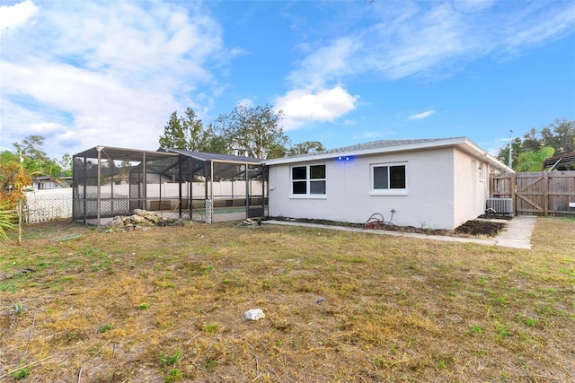 back of property featuring a pool, a yard, and glass enclosure