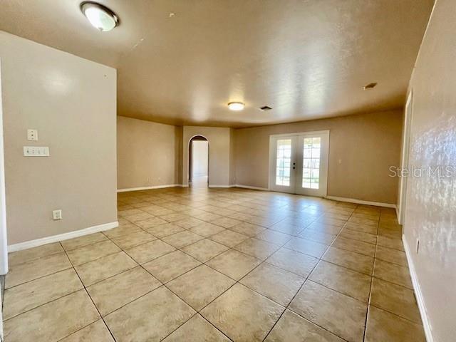 tiled spare room featuring french doors