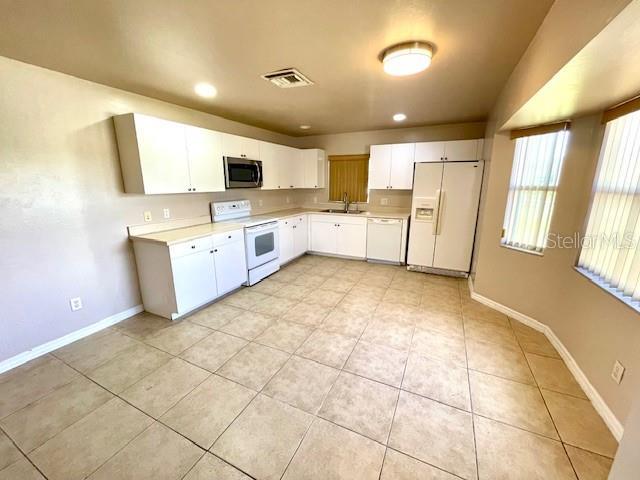 kitchen featuring white cabinetry, sink, white appliances, and light tile patterned floors