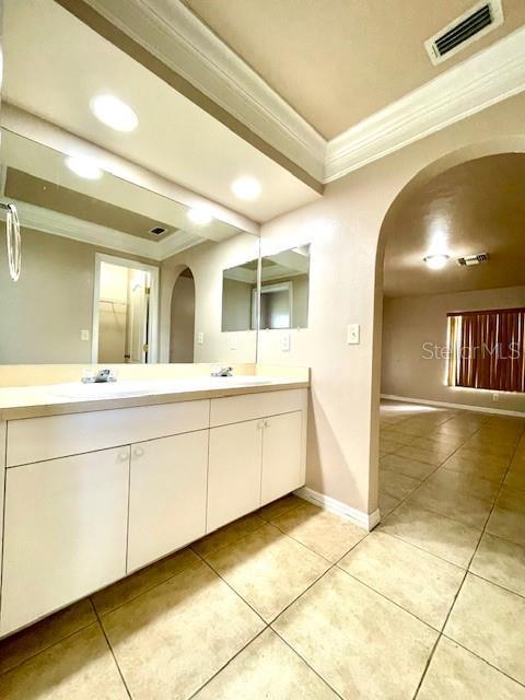 bathroom with tile patterned flooring, ornamental molding, and vanity