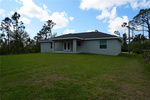 rear view of property featuring stucco siding and a yard