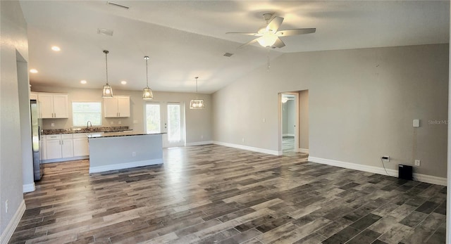 kitchen with a sink, white cabinets, open floor plan, a center island, and decorative light fixtures