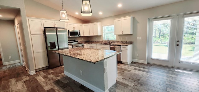 kitchen featuring white cabinets, appliances with stainless steel finishes, a center island, hanging light fixtures, and a sink