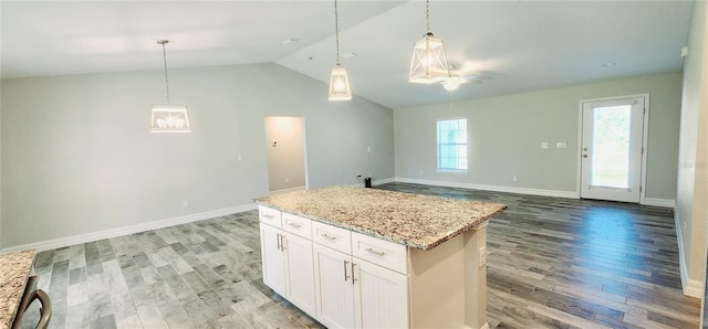 kitchen with a center island, hanging light fixtures, open floor plan, white cabinetry, and light stone countertops