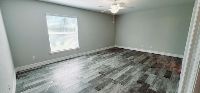 spare room featuring a ceiling fan, dark wood finished floors, and baseboards