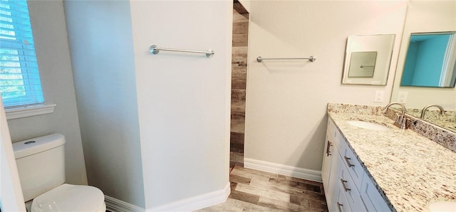 bathroom featuring baseboards, vanity, toilet, and wood finished floors