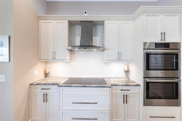 17122 Barcrest Ln, Punta Gorda, FL 33955 - kitchen featuring stainless steel double oven, wall chimney range hood, black electric stovetop, tasteful backsplash, and white cabinets