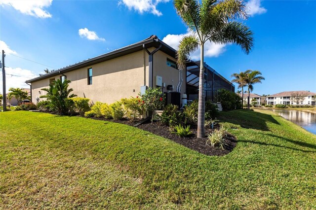 17122 Barcrest Ln, Punta Gorda, FL 33955 - view of property exterior with stucco siding, a yard, glass enclosure, and a water view