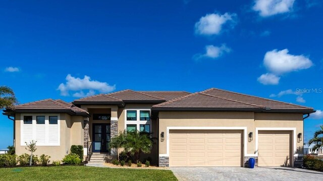 17122 Barcrest Ln, Punta Gorda, FL 33955 - prairie-style house featuring an attached garage, decorative driveway, stucco siding, a front lawn, and stone siding