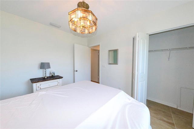 tiled bedroom featuring a notable chandelier and a closet