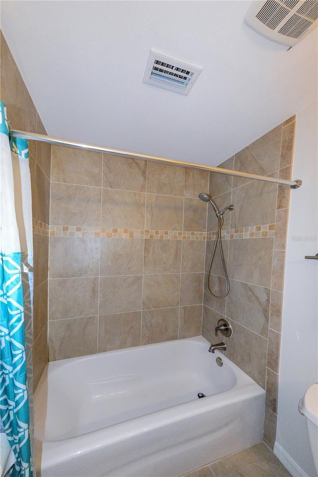 bathroom featuring shower / bathtub combination with curtain, tile patterned flooring, and toilet