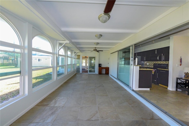 unfurnished sunroom featuring beamed ceiling and ceiling fan