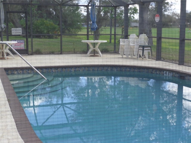 view of pool featuring a lawn and glass enclosure