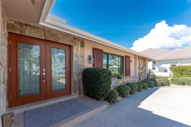 property entrance featuring french doors, a patio, and central air condition unit