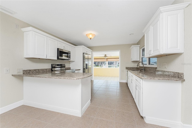 kitchen featuring white cabinetry, sink, light stone counters, and appliances with stainless steel finishes