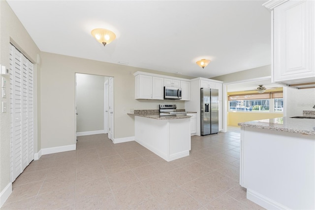 kitchen with light tile patterned floors, appliances with stainless steel finishes, kitchen peninsula, light stone countertops, and white cabinets