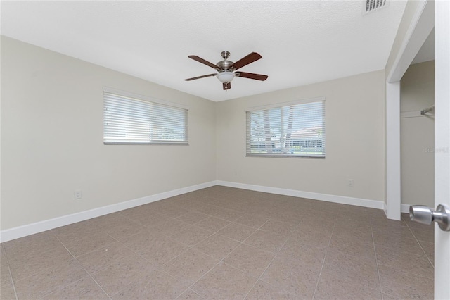 empty room with light tile patterned flooring, ceiling fan, and a healthy amount of sunlight