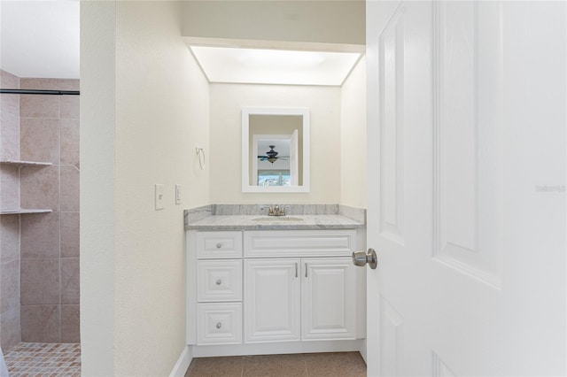 bathroom with a tile shower, vanity, and tile patterned flooring