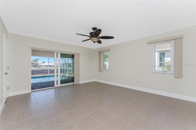 empty room featuring a healthy amount of sunlight, a textured ceiling, and light tile patterned floors