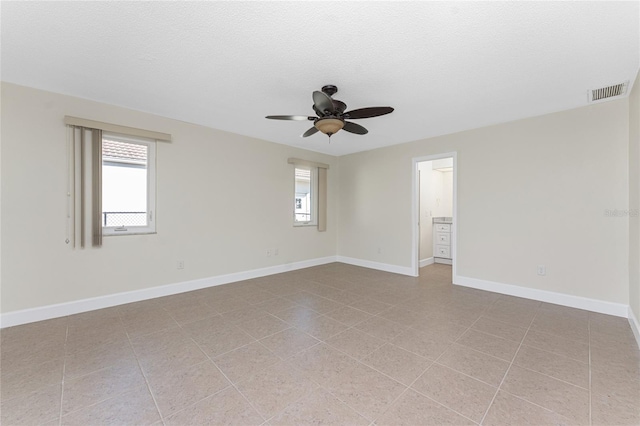 empty room with ceiling fan, a textured ceiling, and light tile patterned flooring