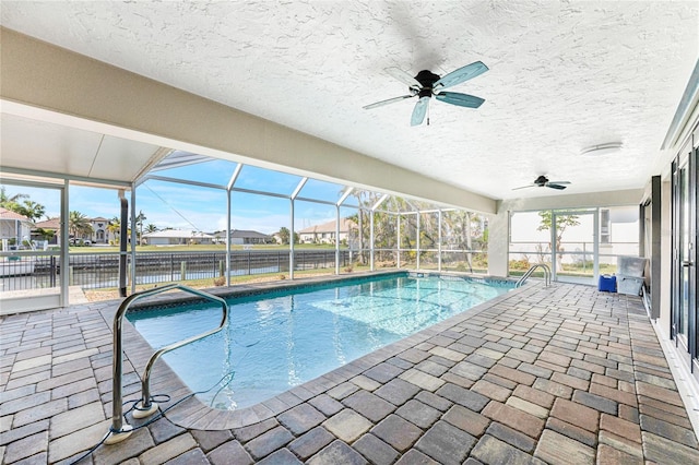 view of pool featuring a patio, a water view, ceiling fan, and glass enclosure