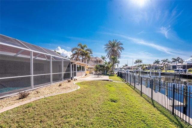 view of yard with a water view, a patio area, and glass enclosure