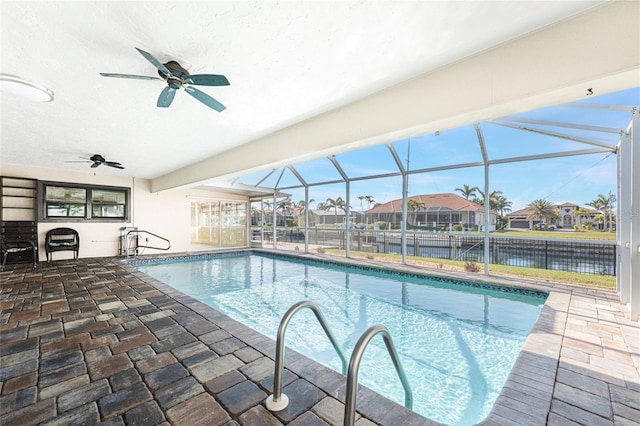 view of pool with ceiling fan, a water view, glass enclosure, and a patio area