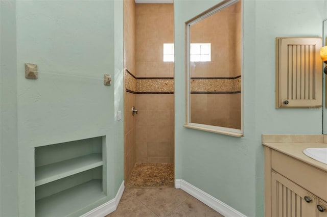 bathroom featuring tile patterned floors, tiled shower, and vanity