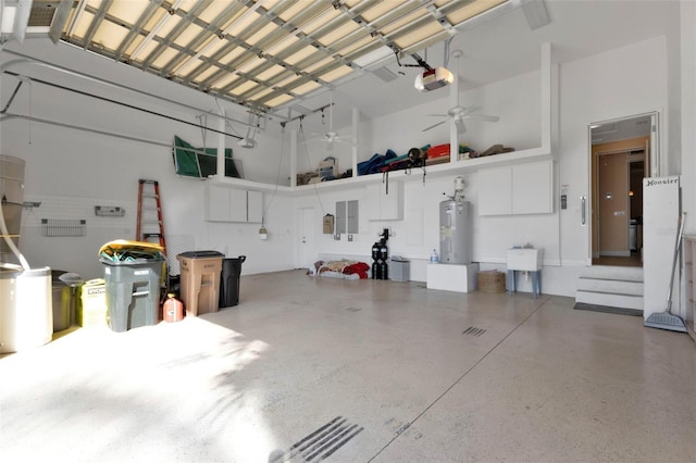 garage with electric panel, ceiling fan, a garage door opener, and water heater