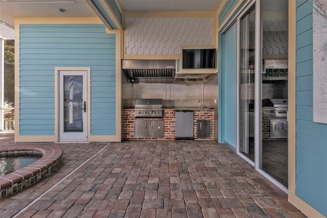 view of patio with exterior kitchen and a grill