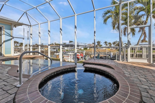 view of swimming pool with glass enclosure, a dock, a patio, and a jacuzzi