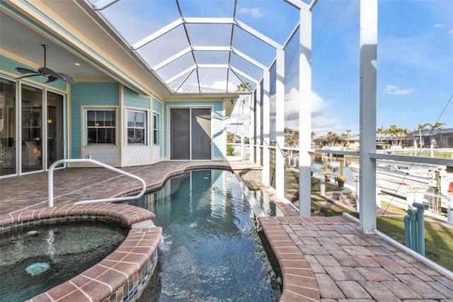 view of pool featuring an in ground hot tub, glass enclosure, ceiling fan, and a patio area