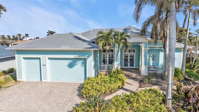 view of front of home with a garage, french doors, and a porch