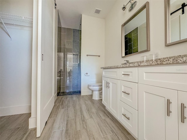 bathroom with an enclosed shower, vanity, and toilet