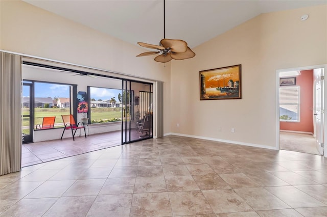 tiled empty room with ceiling fan, plenty of natural light, and high vaulted ceiling