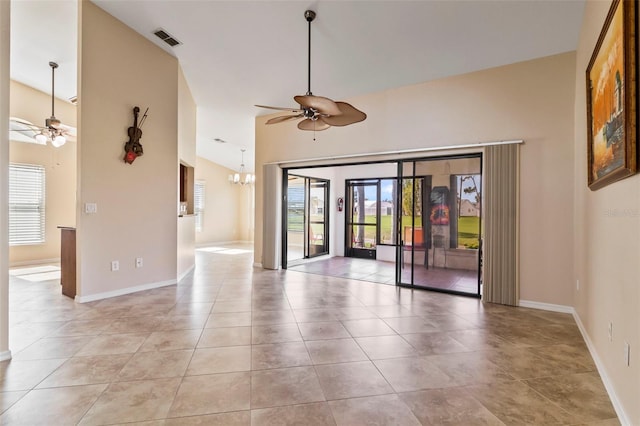 tiled empty room with a high ceiling, a wealth of natural light, and ceiling fan with notable chandelier