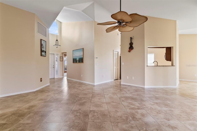 unfurnished living room featuring a towering ceiling, ceiling fan, and light tile patterned flooring