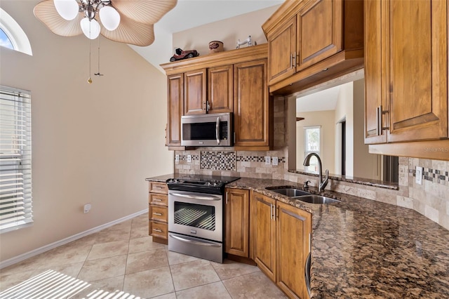 kitchen with sink, light tile patterned floors, stainless steel appliances, tasteful backsplash, and dark stone counters