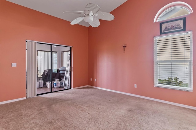 carpeted spare room with ceiling fan, a healthy amount of sunlight, and high vaulted ceiling