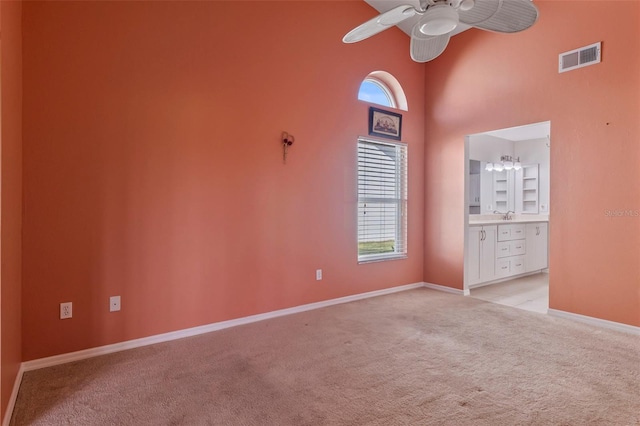 carpeted spare room featuring a high ceiling and ceiling fan