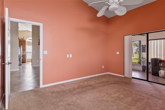 carpeted spare room featuring ceiling fan and high vaulted ceiling