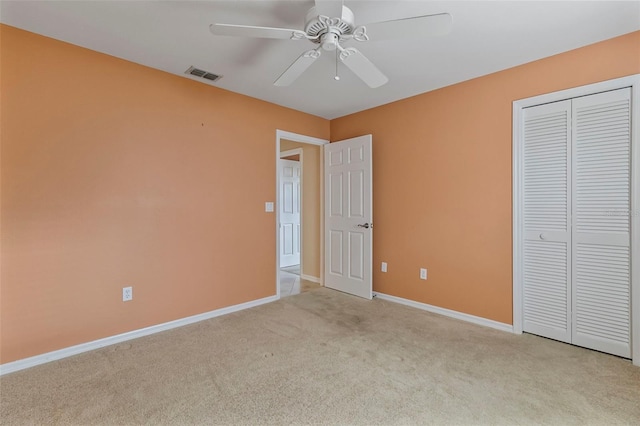 unfurnished bedroom with light colored carpet, a closet, and ceiling fan