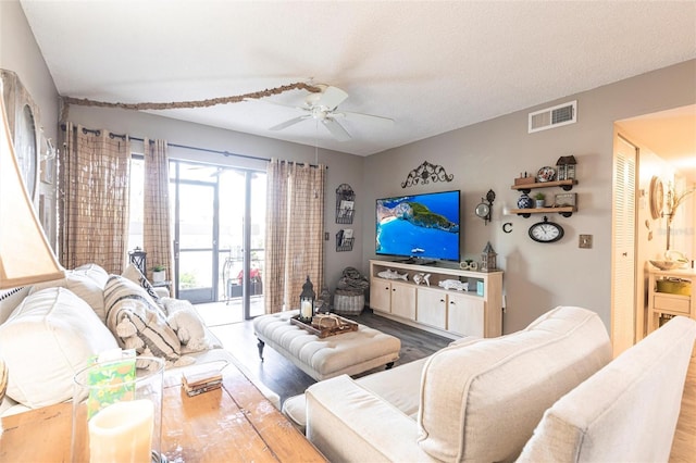 living room featuring wood-type flooring, a textured ceiling, and ceiling fan