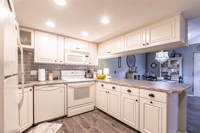 kitchen featuring white cabinetry, white appliances, kitchen peninsula, and hardwood / wood-style flooring