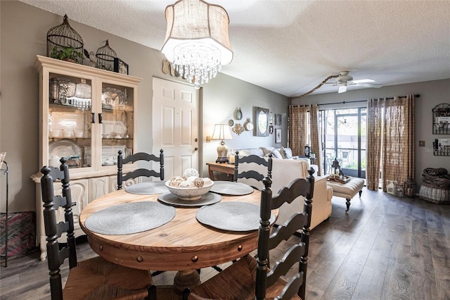 dining room featuring dark hardwood / wood-style floors, ceiling fan with notable chandelier, and a textured ceiling